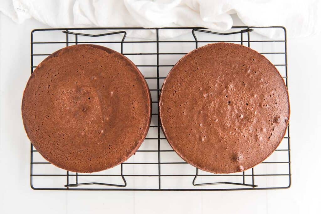 two chocolate cake layers on wire cooling rack
