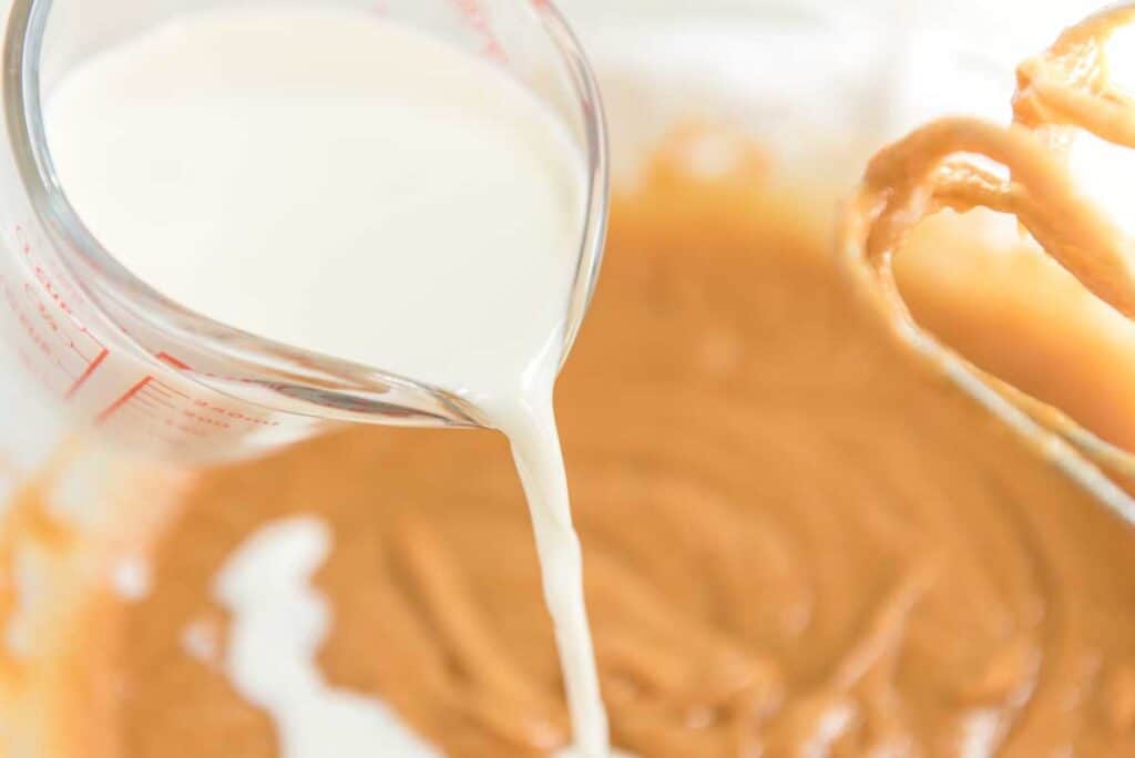 pouring milk into peanut butter cupcake batter 
