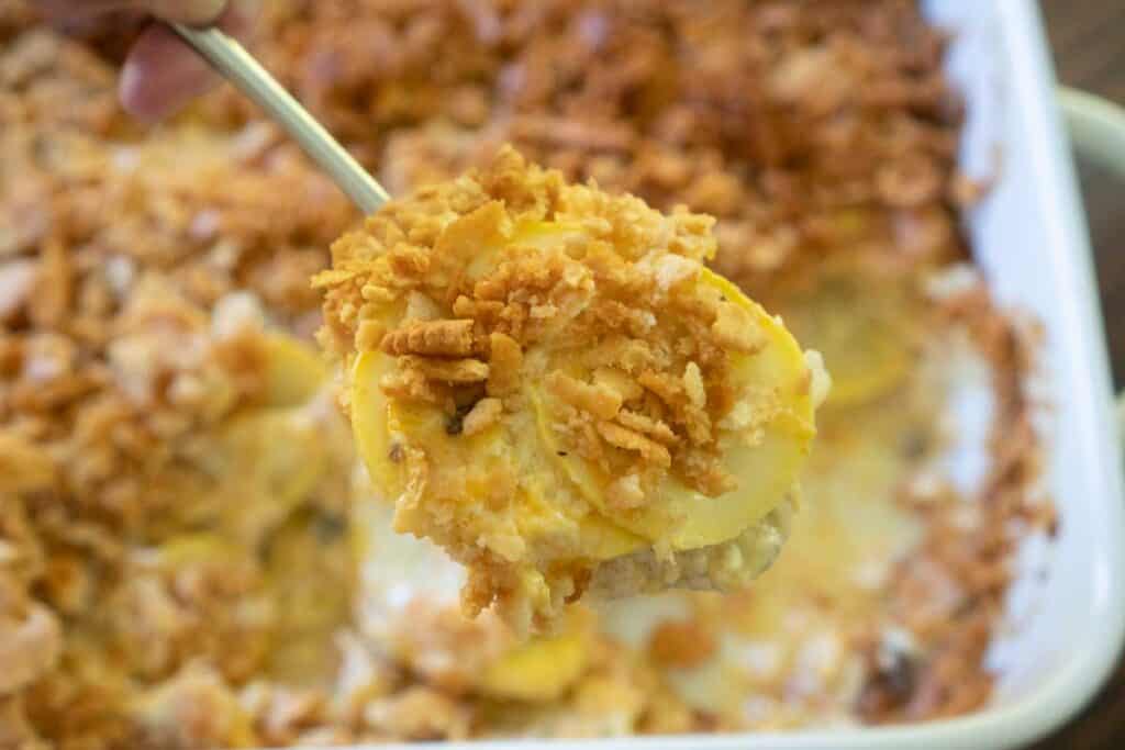 southern squash casserole in a spoon over the rest of the casserole in dish