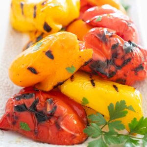 grilled yellow, orange, and red bell peppers on white plate
