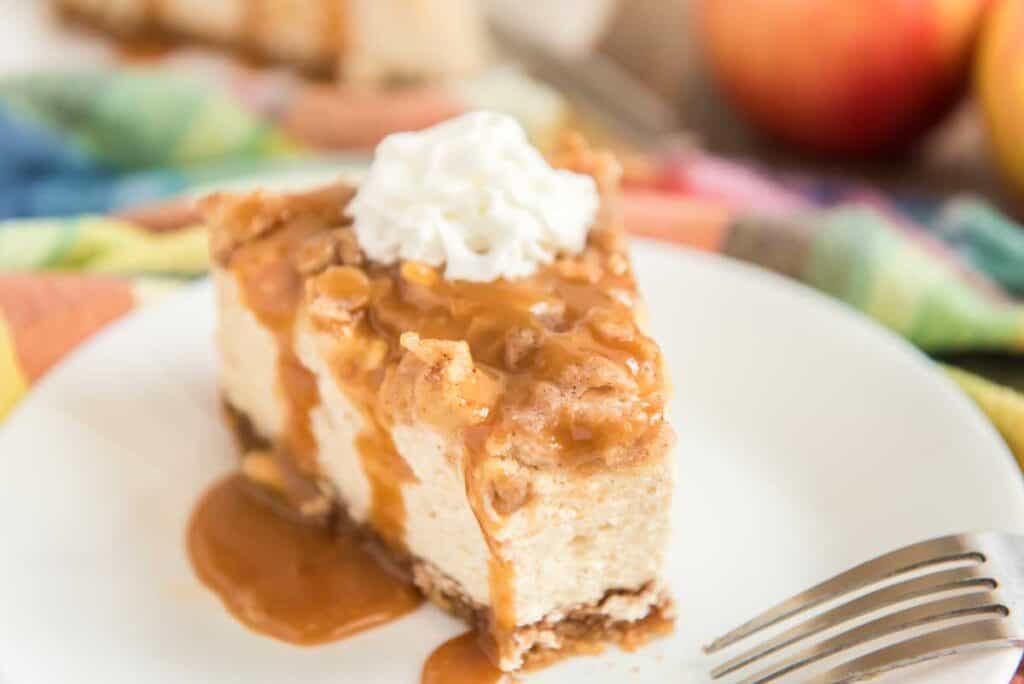 apple crisp cheesecake on white plate with bite taken out and fork