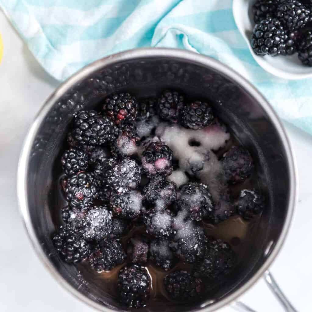 overhead view of blackberries and sugar in pan
