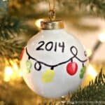 white ornament with fingerprints made to look like string of Christmas lights and the year 2014 written on it