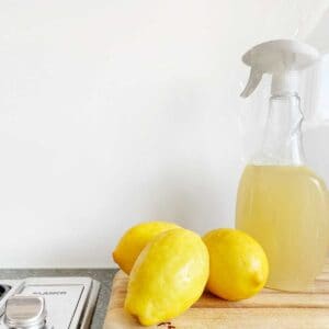 clear spray bottle with yellow liquid and 3 lemons