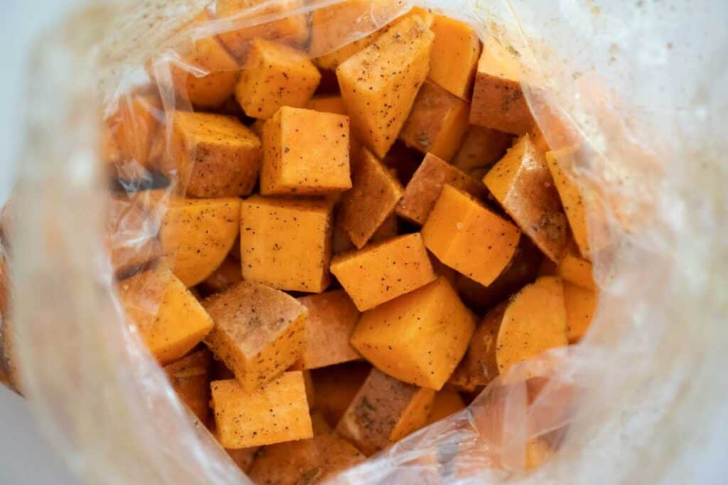 plastic bag with cubes sweet potatoes coated in olive oil and seasonings