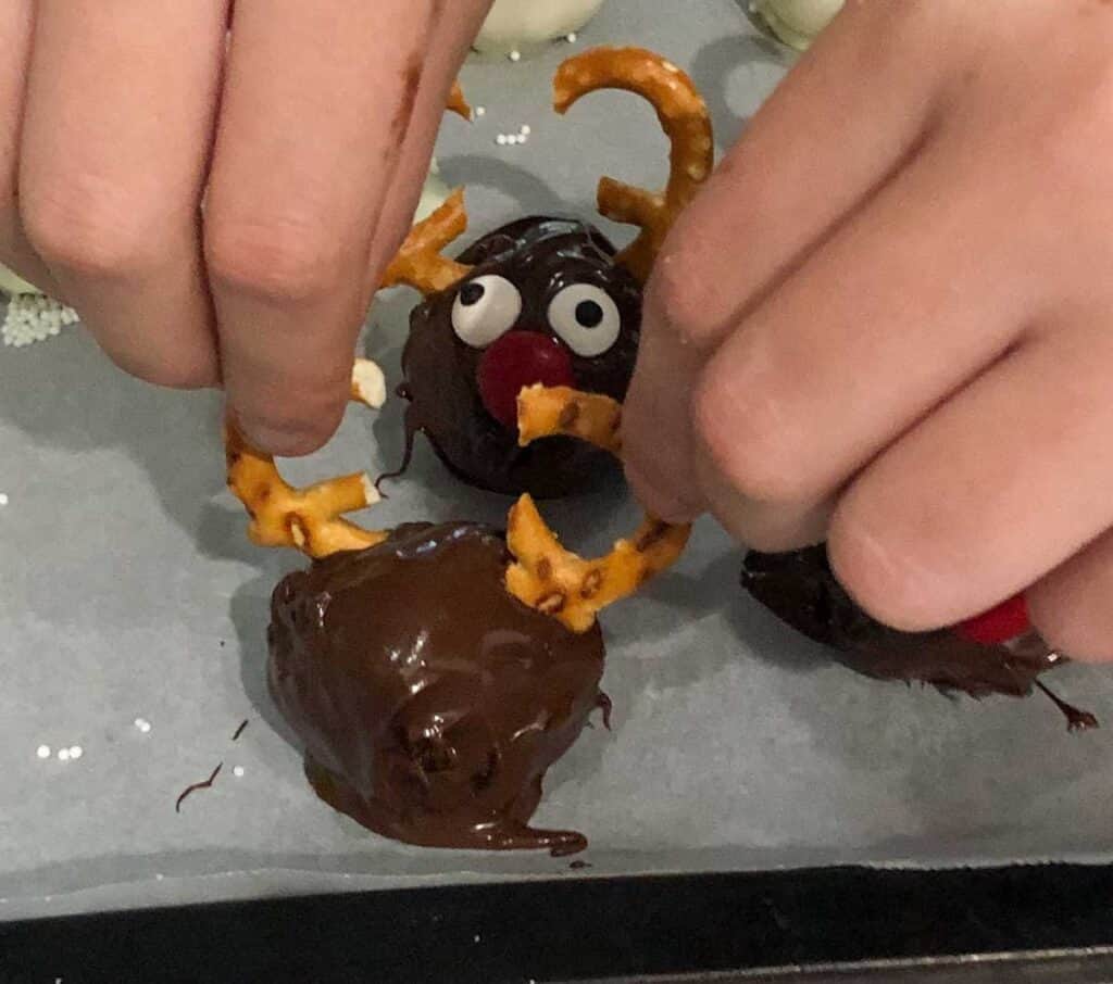 hands pushing broken pretzels into chocolate truffle