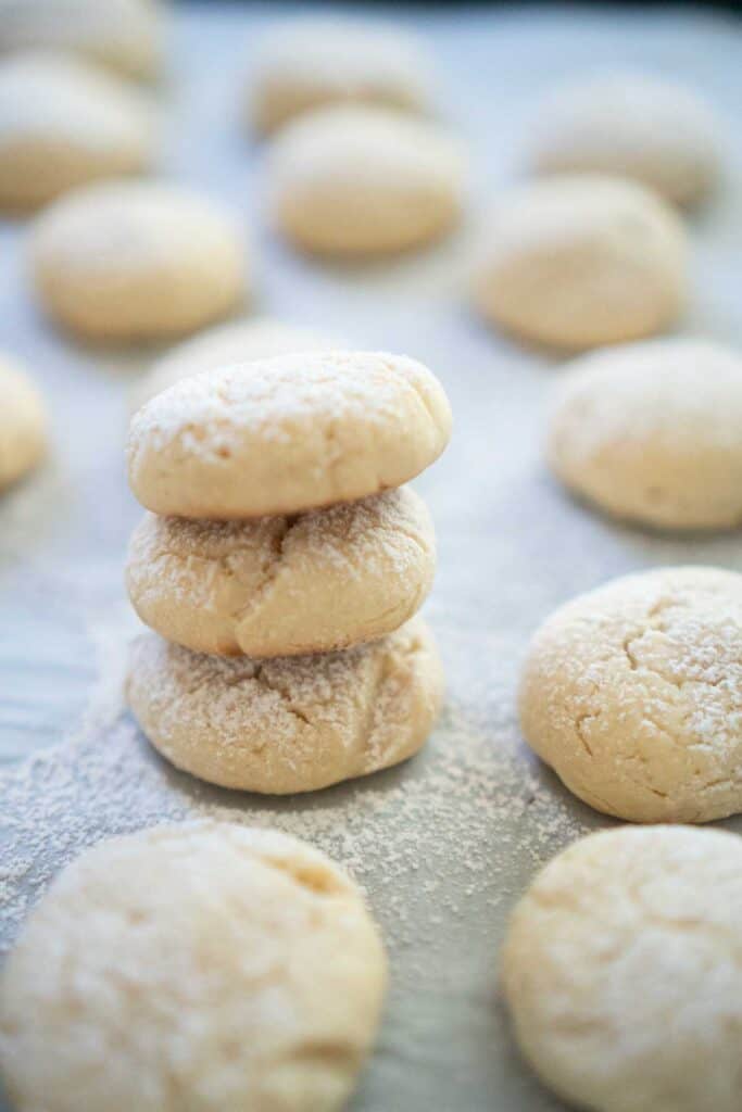 cream cheese cookies with powdered sugar dusting on parchment paper