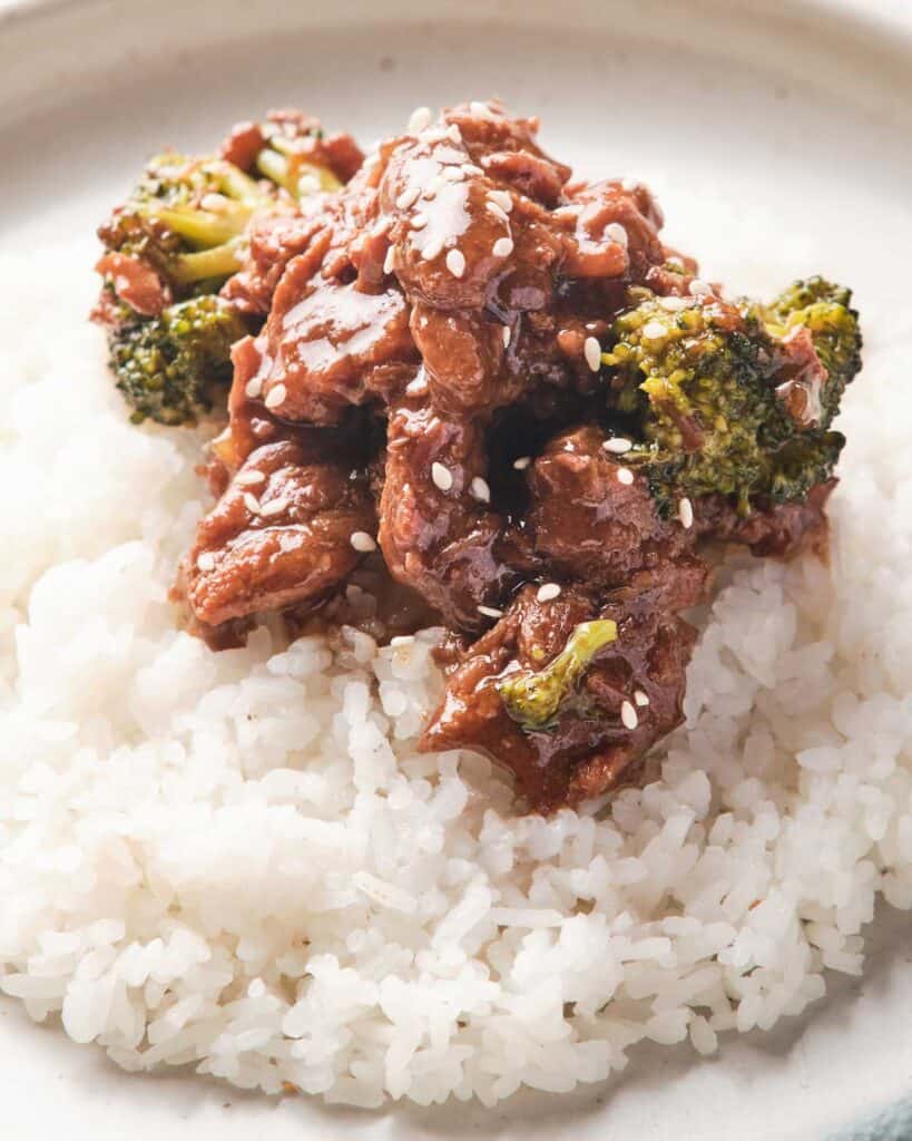 beef and broccoli over rice on white plate