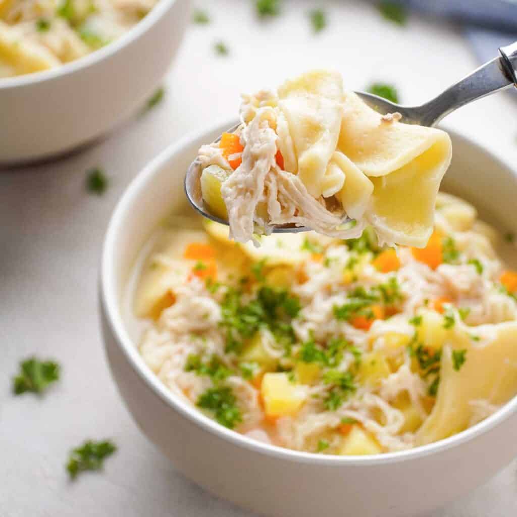 Amish chicken pot pie in spoon held over bowl