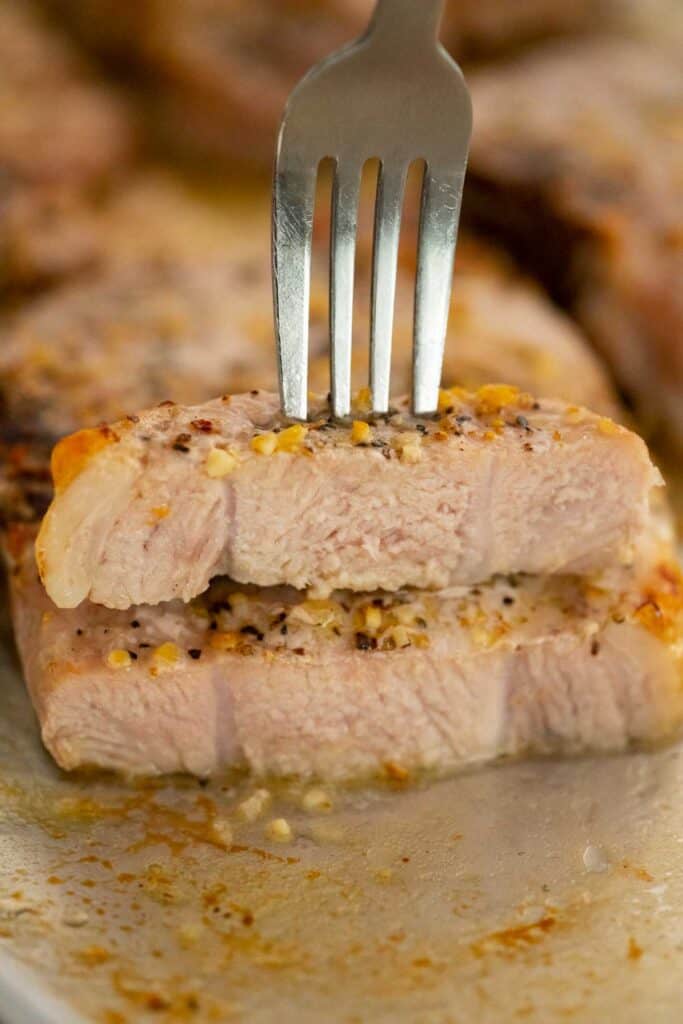 fork piercing piece of pork chop stacked on another pork chop