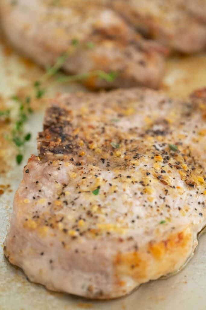 baked pork chop with thyme sprigs on pan