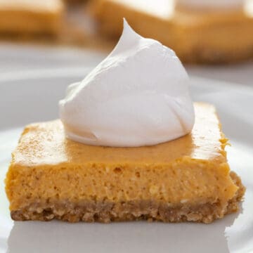 close up of pumpkin cheesecake bar with whipped cream on top