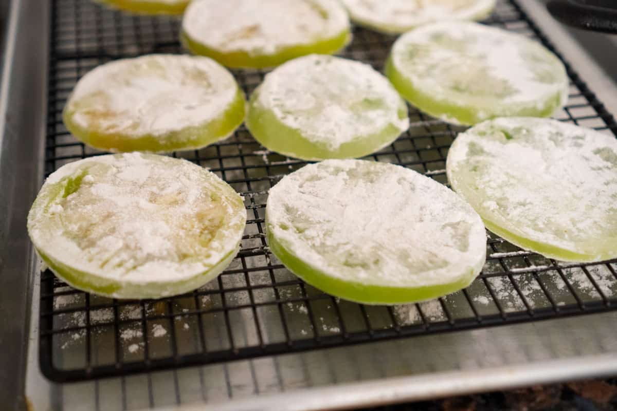 Green tomato slices dipped in flour on a wire rack