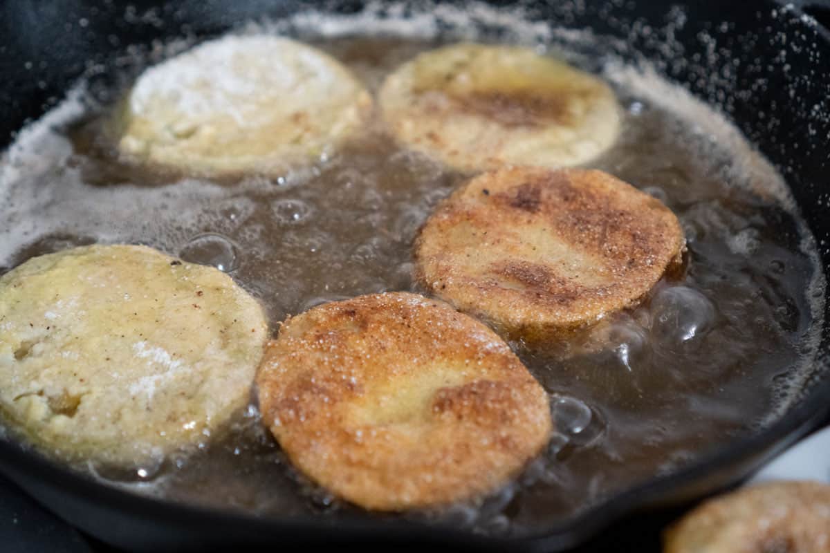 green tomatoes frying in cast iron skillet