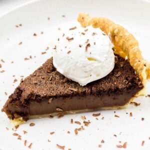 slice of chocolate chess pie topped with scoop of vanilla ice cream and chocolate shavings