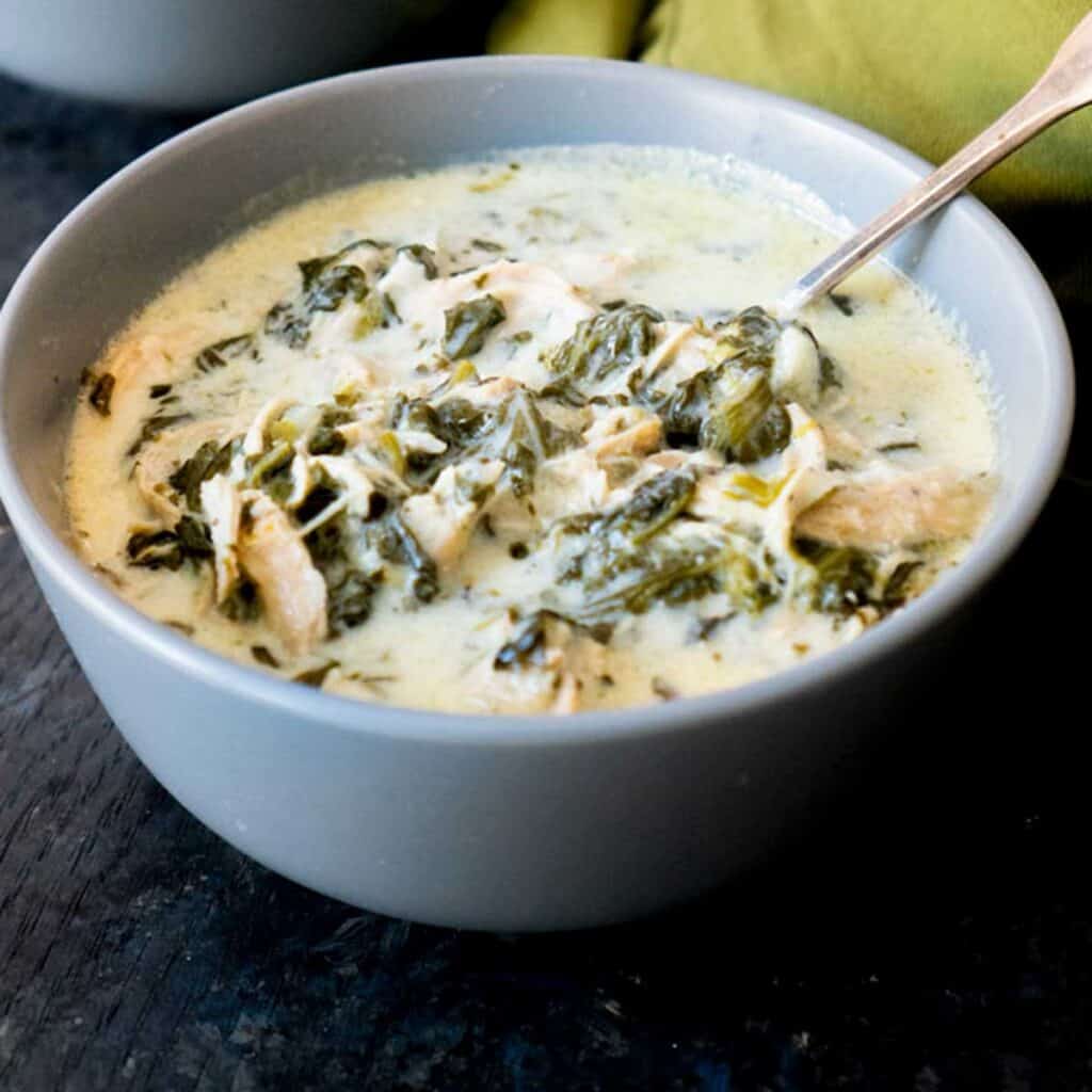 chicken spinach creamy soup in blue bowl with spoon