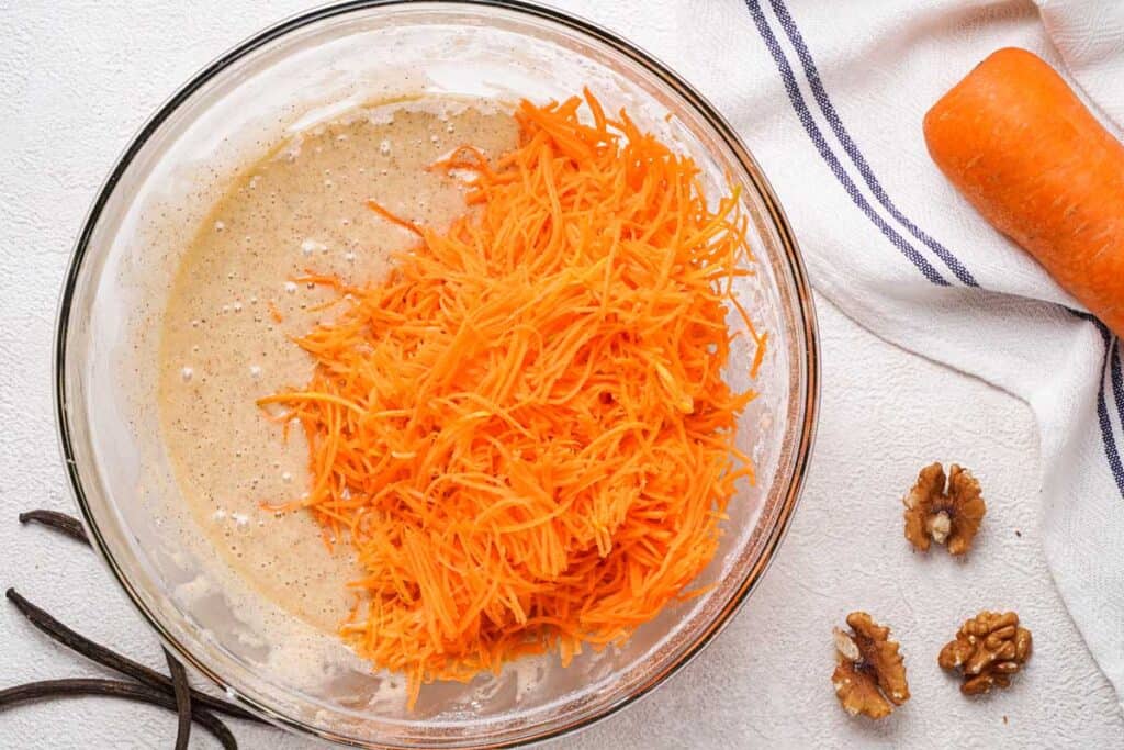 carrot cake muffin batter with shredded carrots in glass bowl