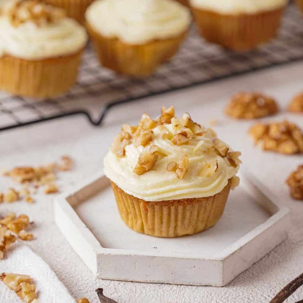 carrot cake muffin topped with cream cheese frosting and chopped walnuts