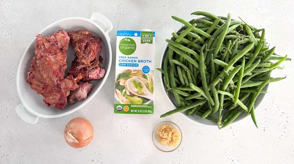 turkey necks, broth, onion, garlic, and green beans for southern green bean recipe on counter