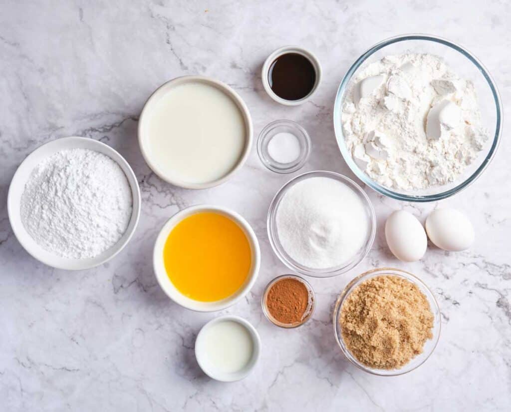 ingredients for cinnamon roll coffee cake in bowls on marble counter
