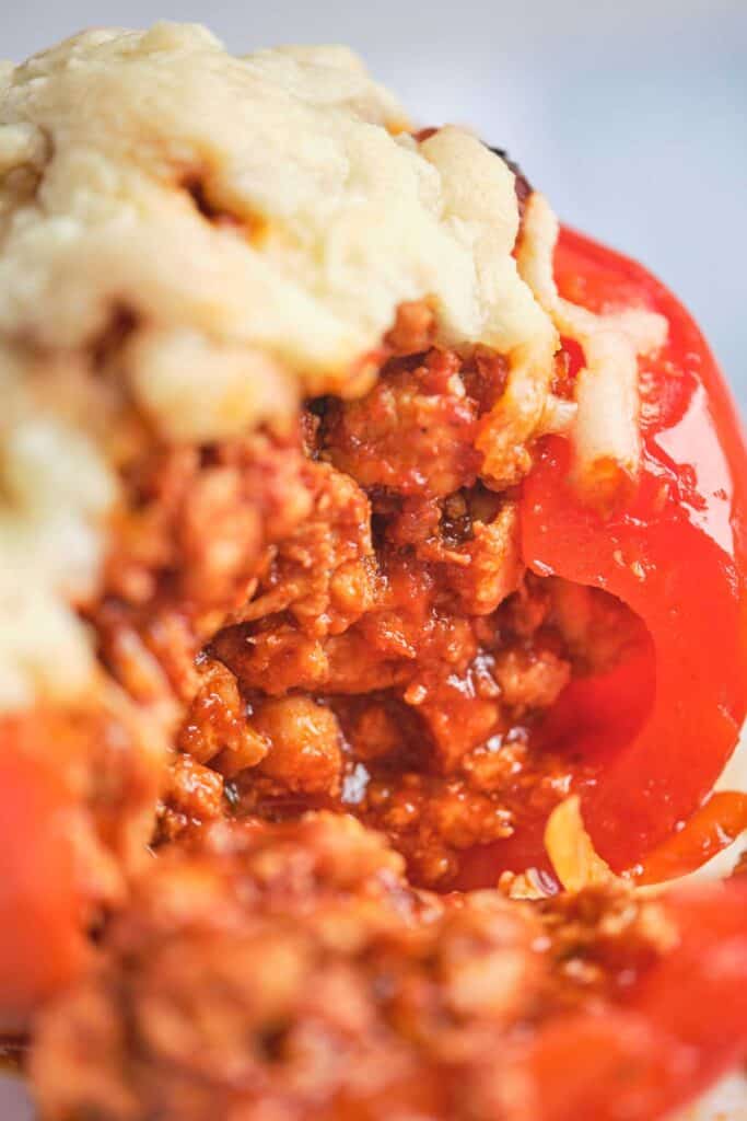 extreme close up shot of turkey stuffed red bell pepper topped with cheese