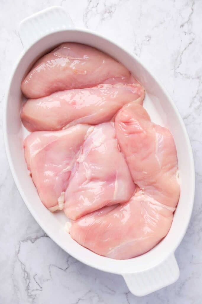 raw chicken breast in white baking dish