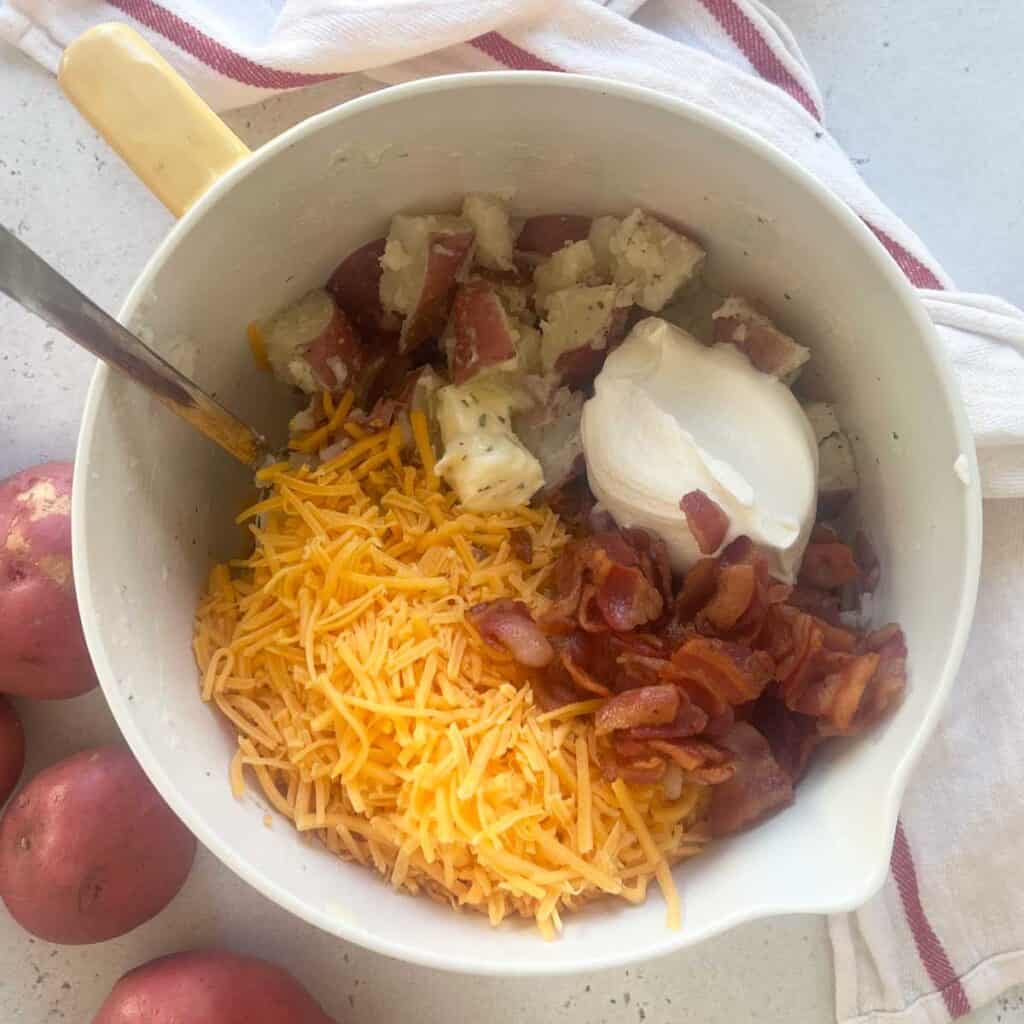 potatoes, bacon, cheese, and sour cream in mixing bowl