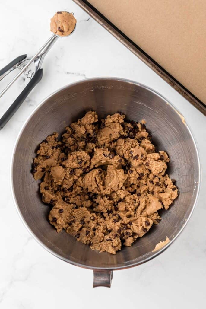 cookie dough in mixing bowl with cookie scoop