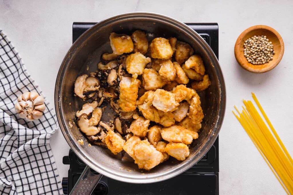chicken and mushrooms cooking in pan