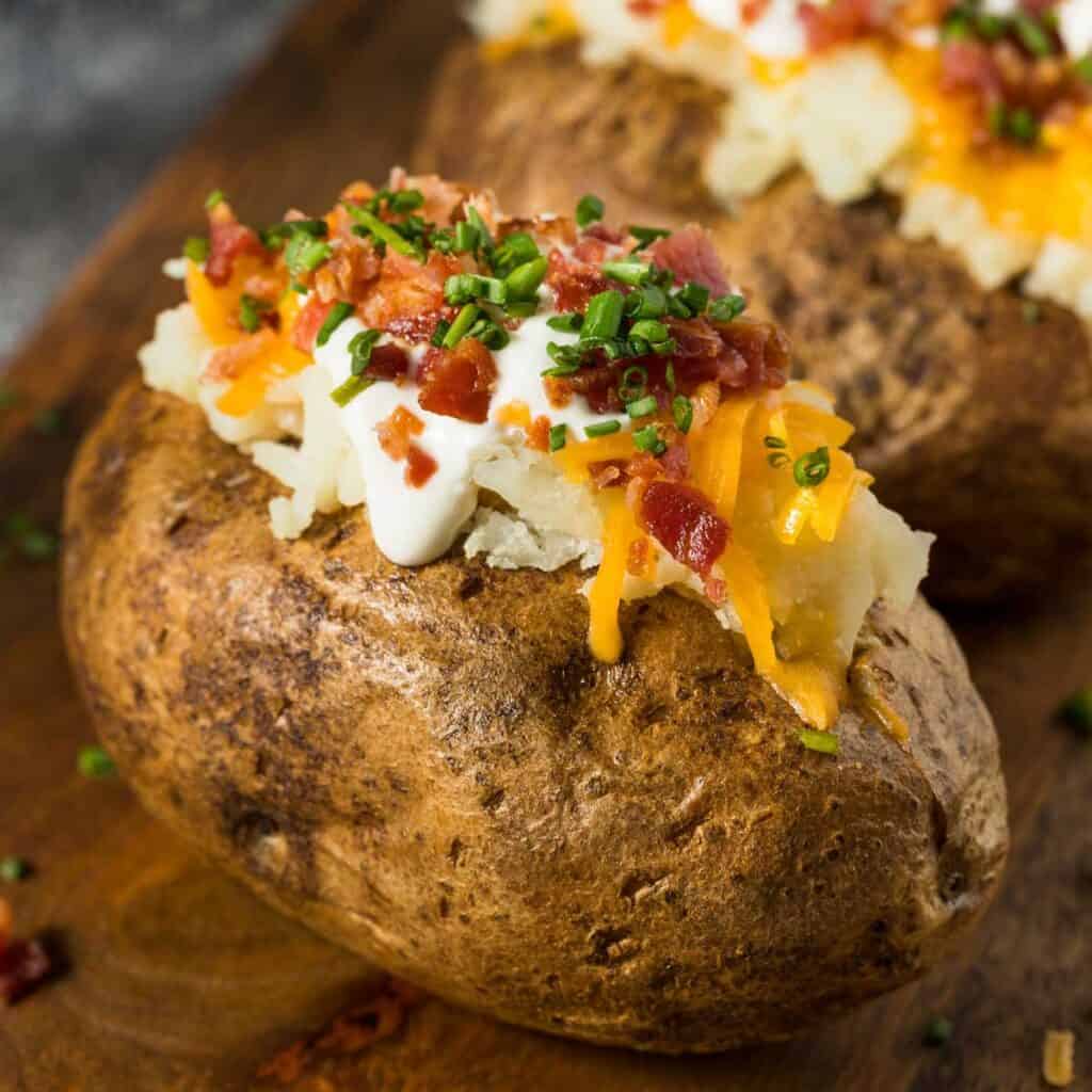 baked potato with sour cream, bacon, cheese, and chives