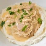 Instant Pot chicken and gravy in white bowl over mashed potatoes