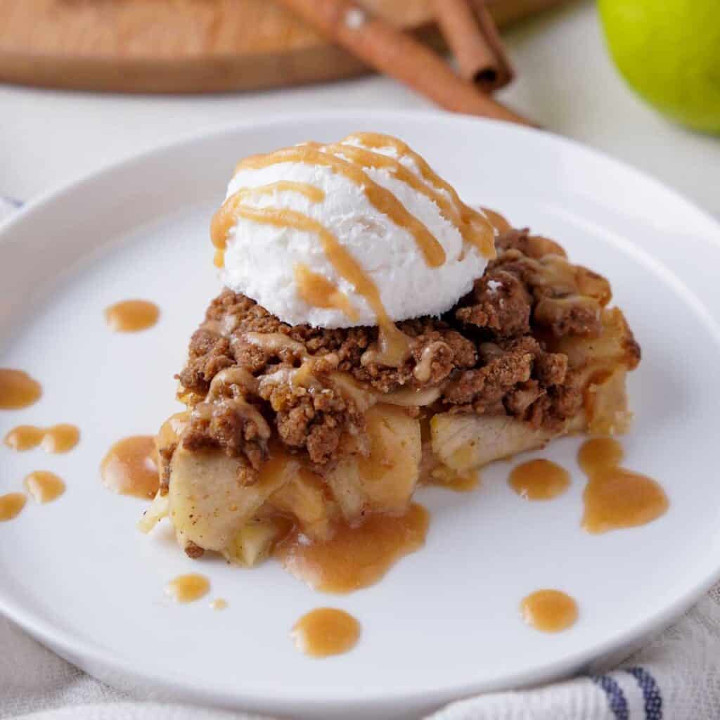 slice of Dutch apple crumb pie on white plate with scoop of ice cream on top