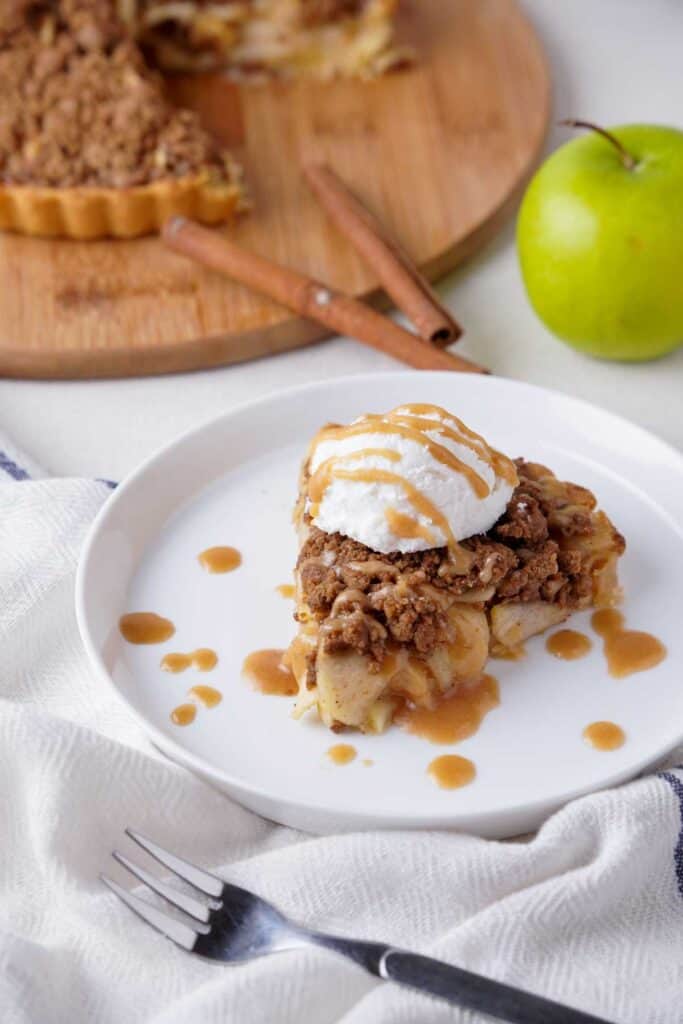 slice of apple pie topped with ice cream in front of remaining pie