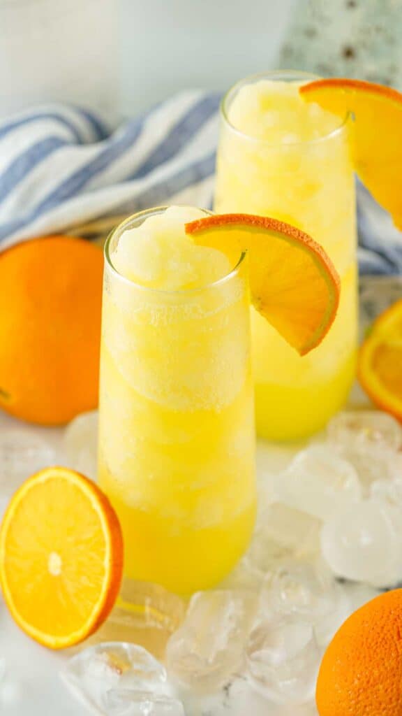 two stemless flutes of frozen mimosas with orange slices