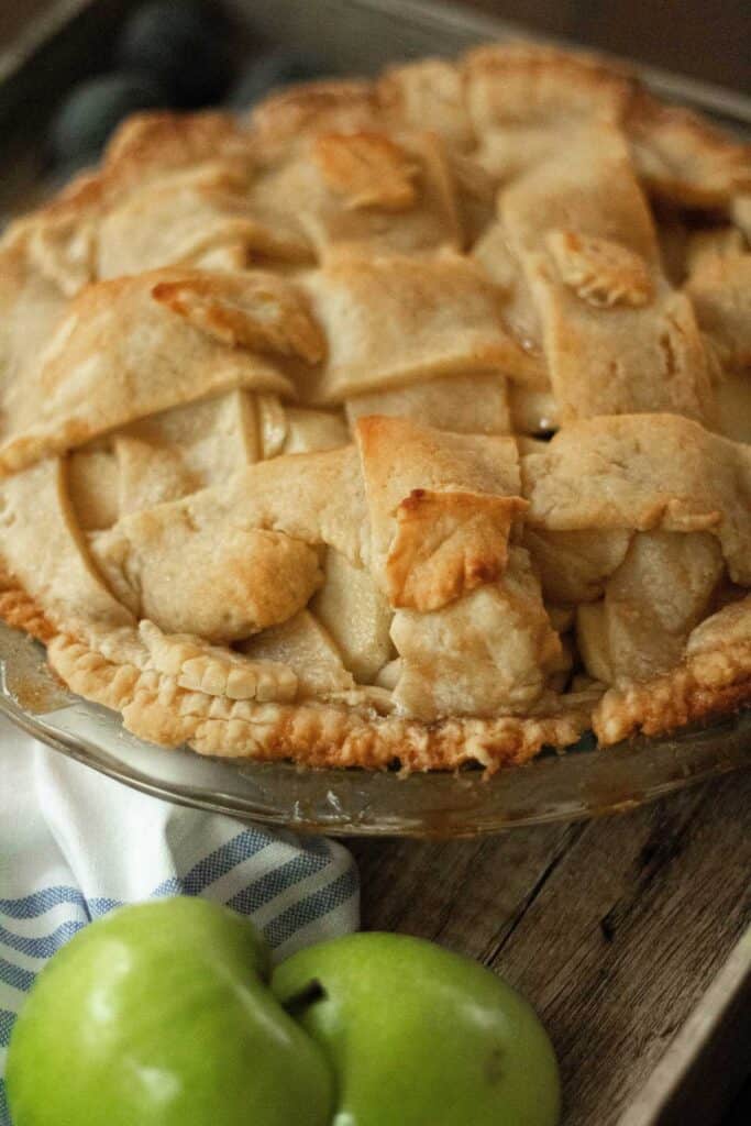 close up of apple pie with two green apples