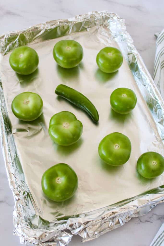 tomatillos and pepper before roasting on foil lined baking sheet