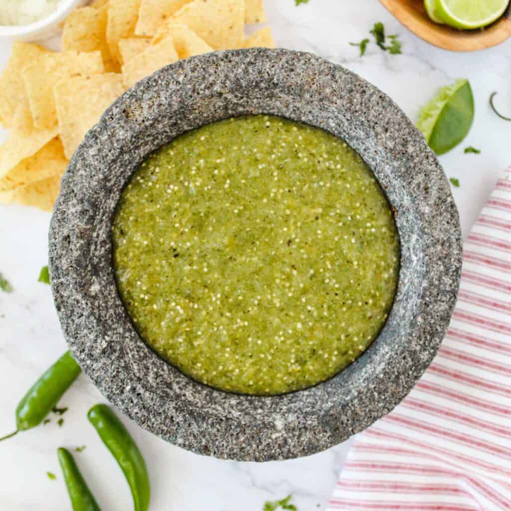 salsa verde in stone bowl with chips in background