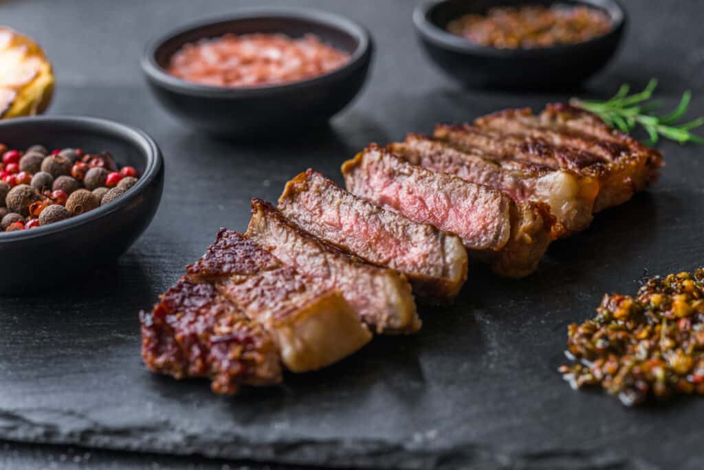 sliced tri-tip steak on slate cutting board