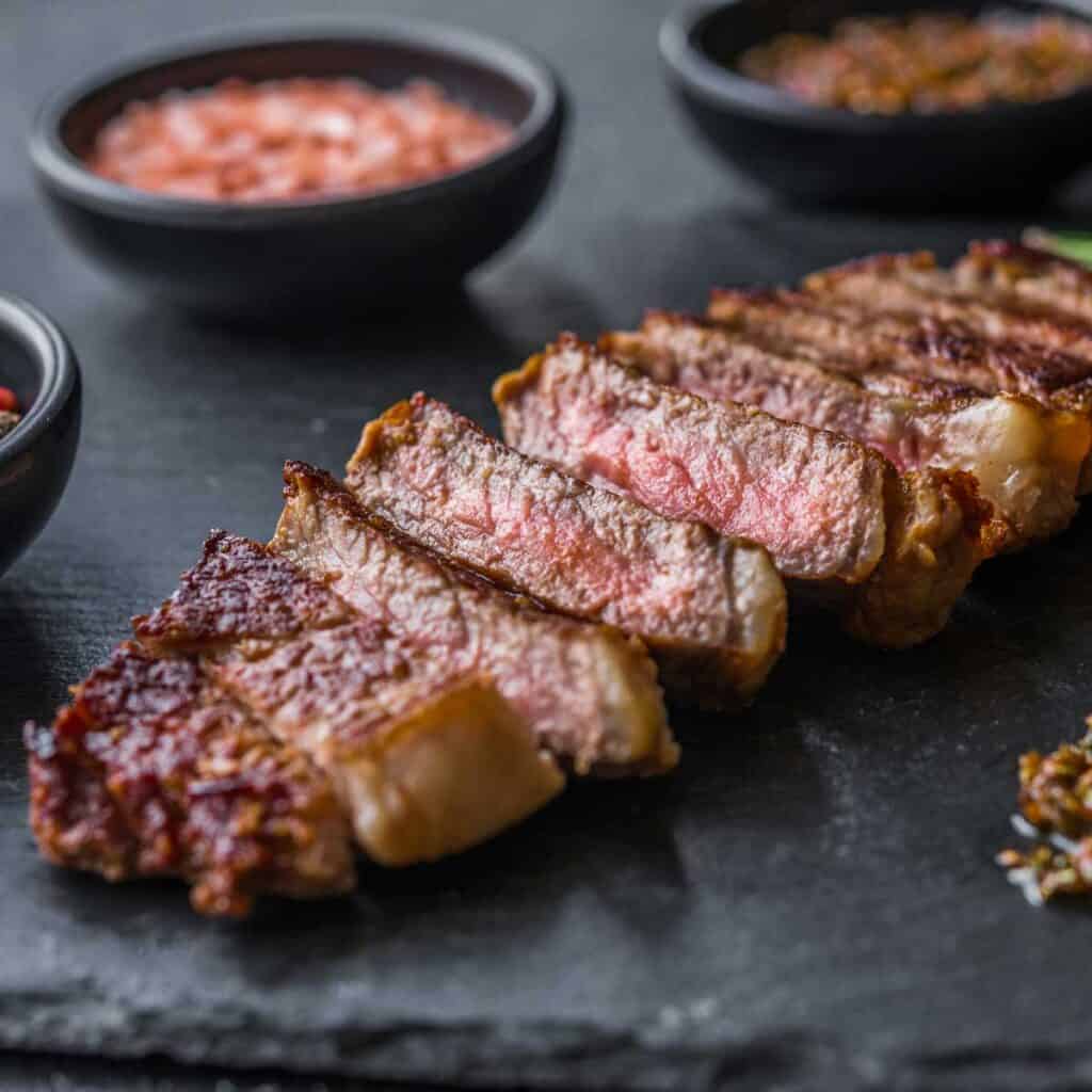 sliced tri tip steak on slate cutting board