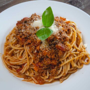 spaghetti on white plate with basil garnish