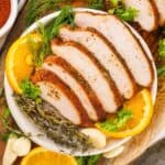 sliced cajun smoked turkey breast on plate with orange slices and herbs