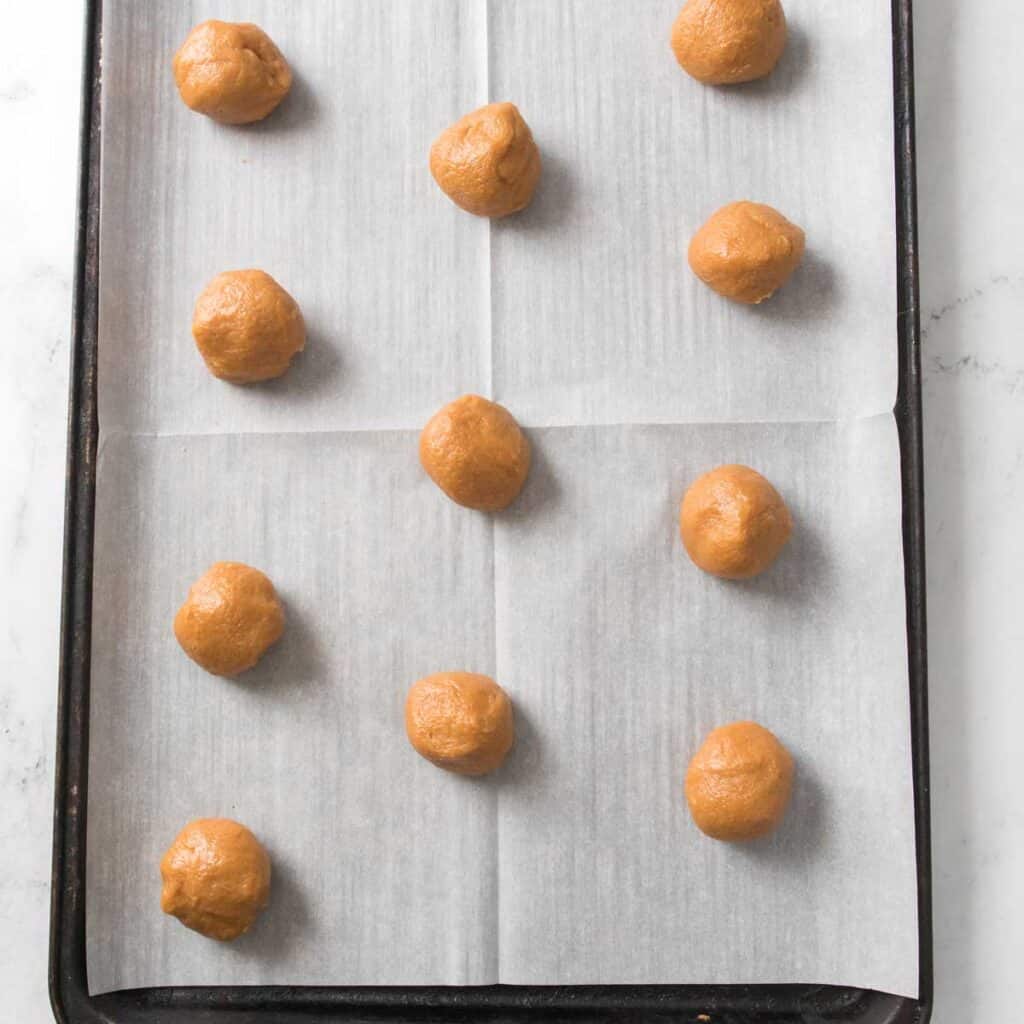 peanut butter cookie dough rolled into balls on cookie sheet