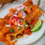 slow cooker enchiladas on white plate with pico de gallo