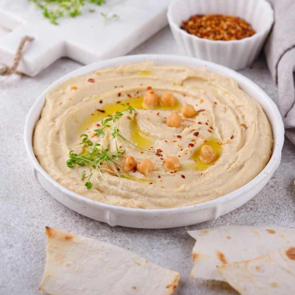 white bowl with hummus and pita pieces