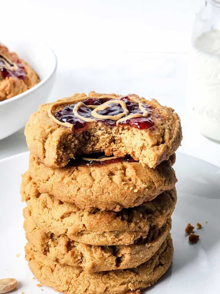 stack of peanut butter and jelly cookies with bite take out of the top cookie