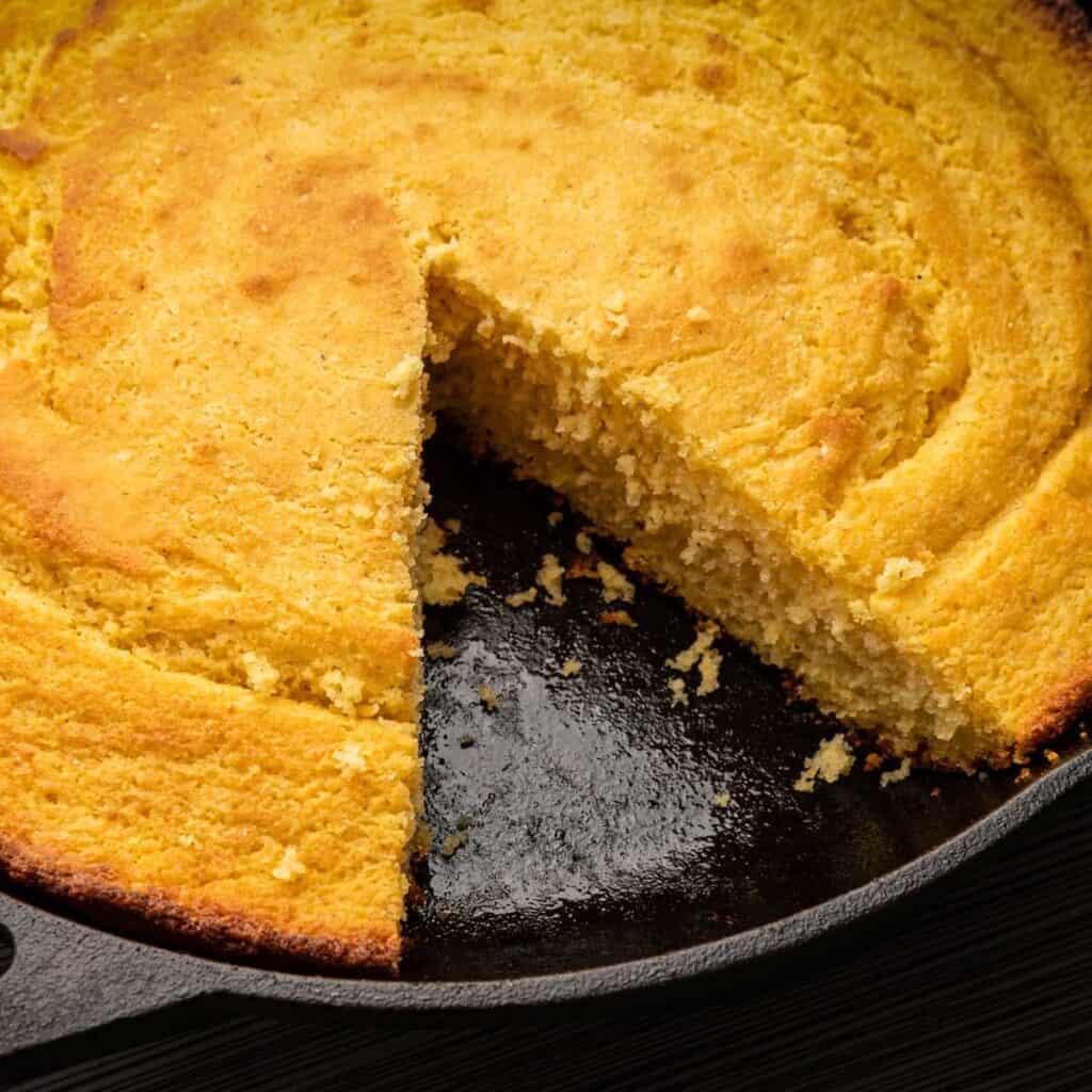 cornbread in skillet with one slice removed