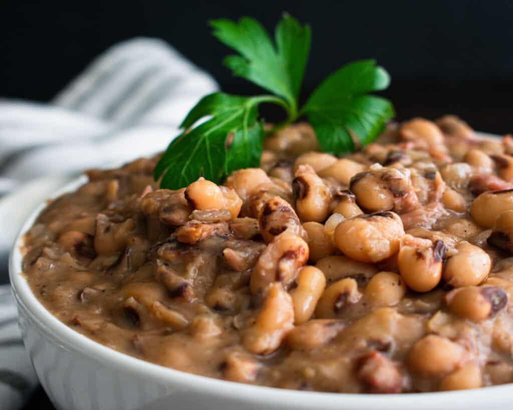 black eyed peas in white bowl with parsley spirg