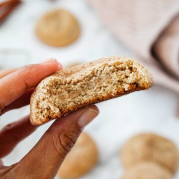 hand holding half a chewy snickerdoodle cookie