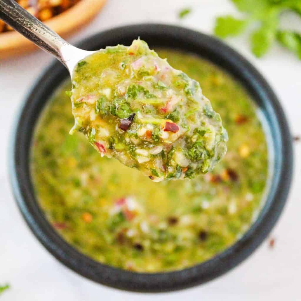 spoonful of cilantro chimichurri sauce over bowl of remaining sauce
