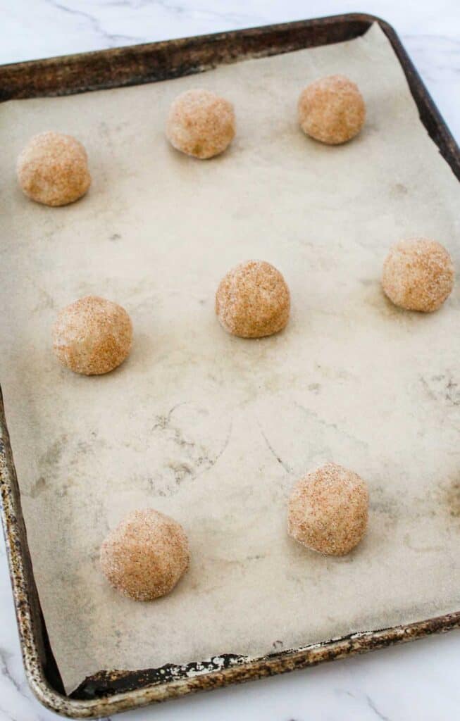 unbaked snickerdoodle dough balls on baking sheet with parchment paper